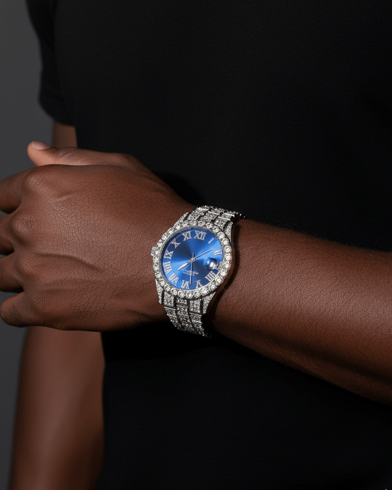 Person wearing a watch with a blue face and diamond-studded band on a dark background