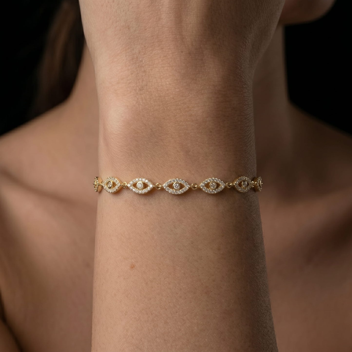 Gold bracelet with diamond accents on a wrist against a neutral background