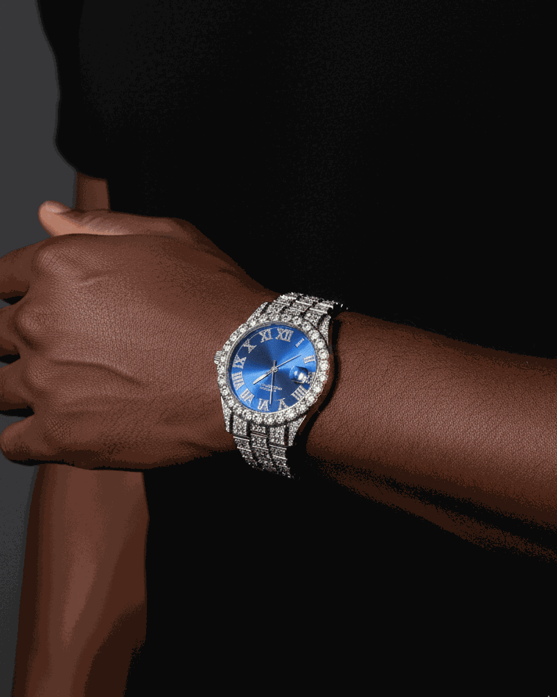 Person wearing a watch with a blue face and diamond-studded band on a dark background