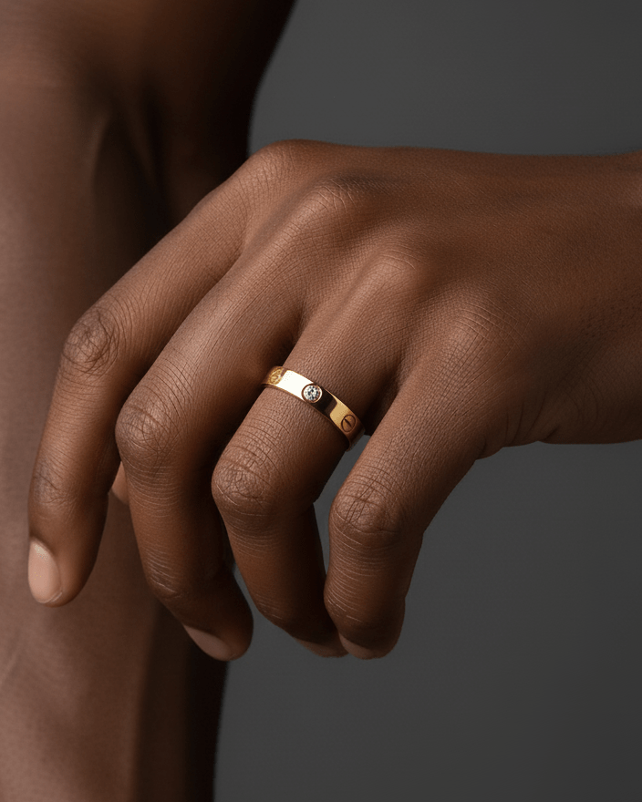 Close-up of a hand wearing a gold ring on a dark background