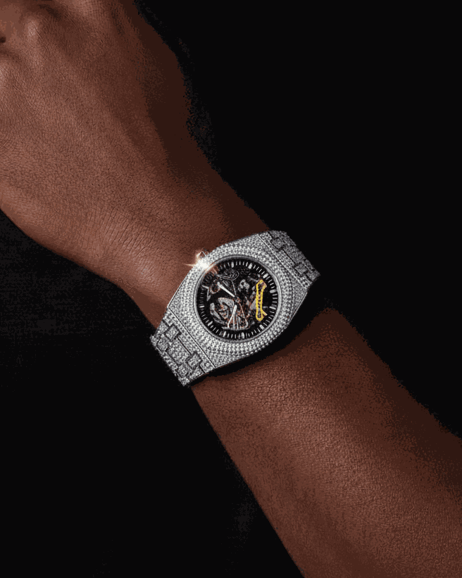 Person wearing a silver watch with a black face on a dark background